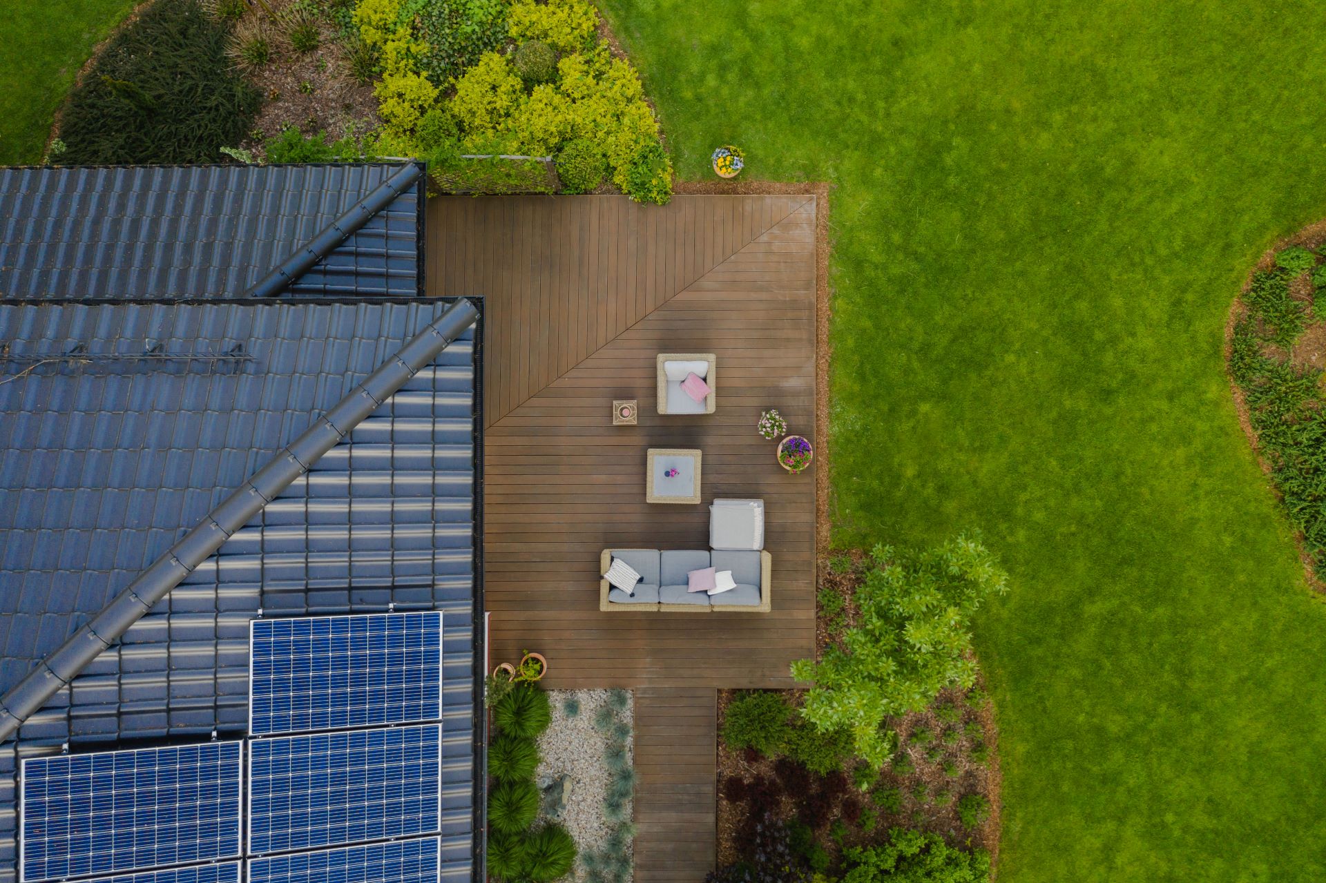 Draufsicht auf ein Vorstadthaus mit grünem Garten und Holzterrasse