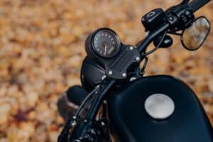 Nahaufnahme eines Motorrad-Tachos mit buntem Herbstlaub im Hintergrund; vermittelt Fahrgefühl, Präzision und den passenden Einsatz von Shoei Helmen.